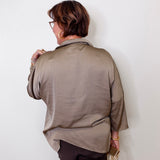 Person wearing a beige top against a white wall