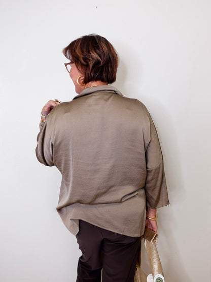 Person wearing a beige top against a white wall