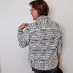 Woman wearing a patterned jacket against a white wall