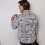 Woman wearing a patterned jacket against a white wall