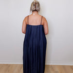Person wearing a navy blue dress standing against a white wall.