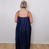 Person wearing a navy blue dress standing against a white wall.