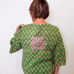 Person wearing a green patterned blouse with a white background