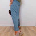 Person wearing blue jeans and beige sandals on a wooden floor.