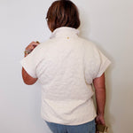 Person wearing a white shirt and blue jeans against a plain background