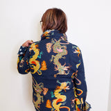 Person wearing a navy blue jacket with colorful dragon patterns against a white background