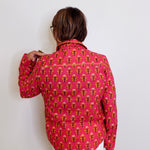 Person wearing a pink patterned shirt against a white wall