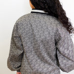 Person wearing a patterned top with a plain background