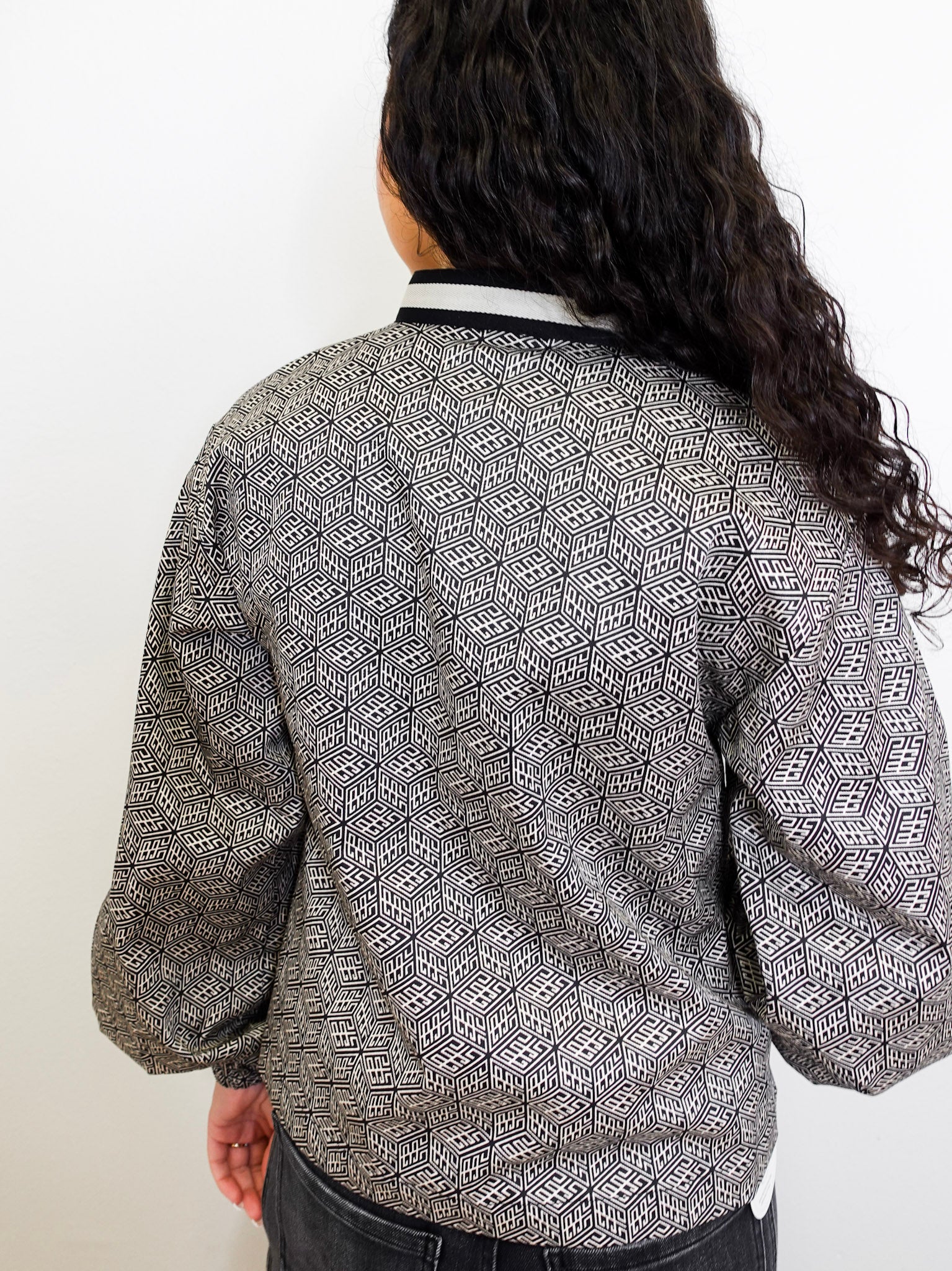 Person wearing a patterned top with a plain background