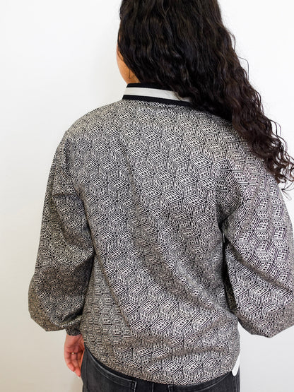 Person wearing a patterned top with a plain background