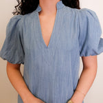 Woman wearing a blue dress with puffed sleeves against a neutral background