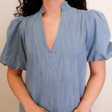 Woman wearing a blue dress with puffed sleeves against a neutral background
