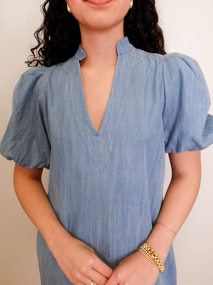 Woman wearing a blue dress with puffed sleeves against a neutral background