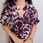 Woman wearing a maroon and white patterned dress against a plain background