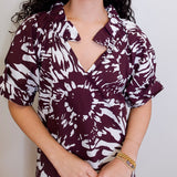 Woman wearing a maroon and white patterned dress against a plain background