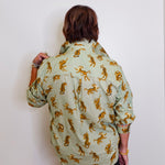 Person wearing a light green shirt with gold tiger patterns against a white background
