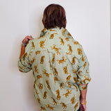 Person wearing a light green shirt with gold tiger patterns against a white background