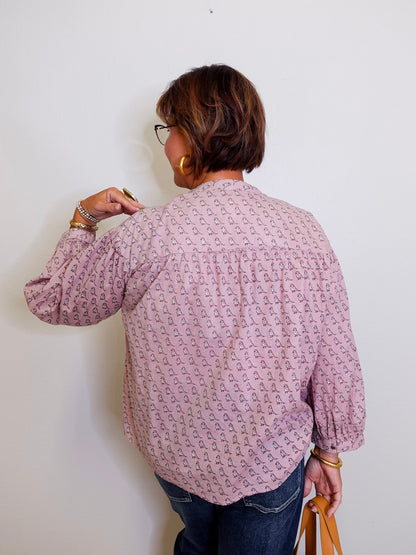 Person wearing a patterned shirt against a white wall