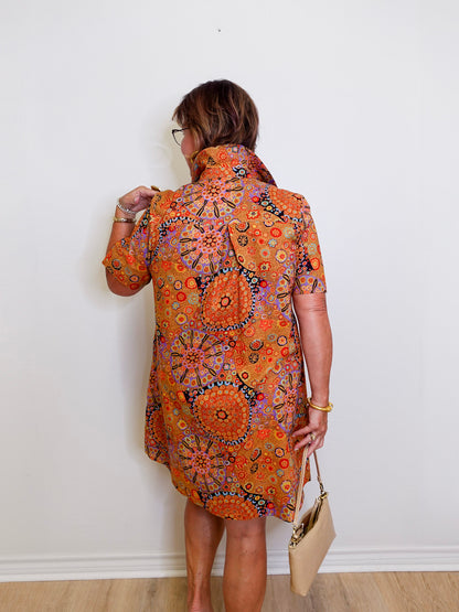 Woman wearing a patterned dress against a white wall