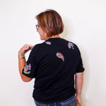 Person wearing a black t-shirt with colorful designs on the back against a white background