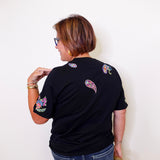 Person wearing a black t-shirt with colorful designs on the back against a white background