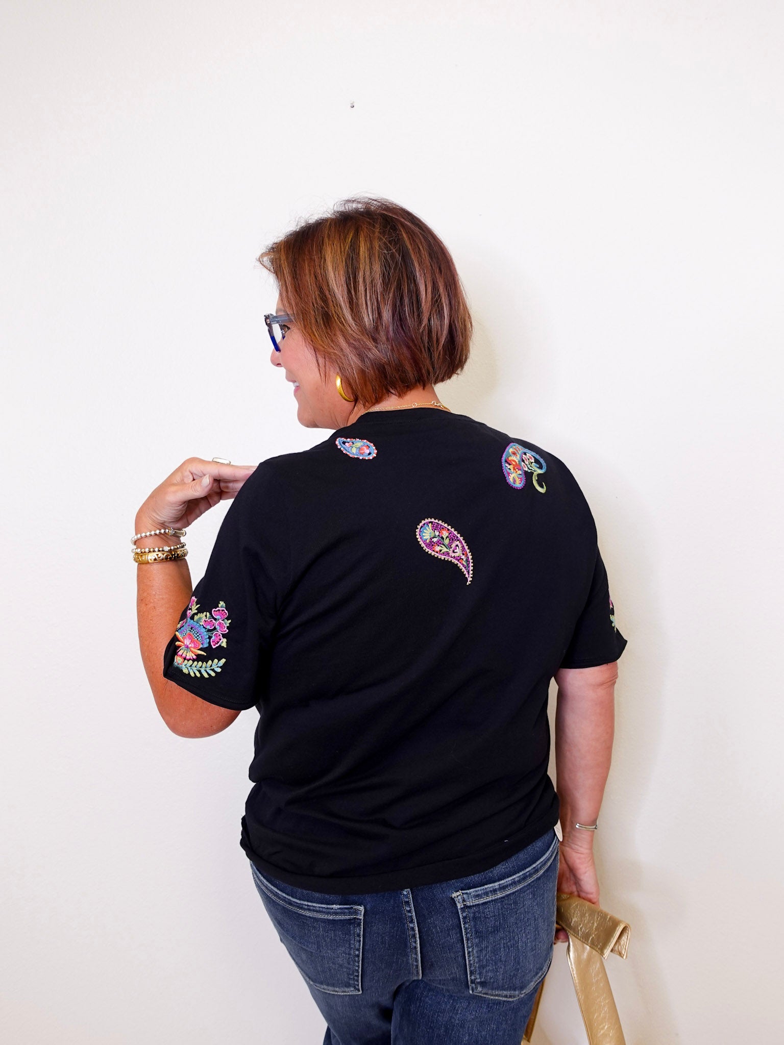 Person wearing a black t-shirt with colorful designs on the back against a white background