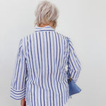 Person wearing a blue and white striped shirt against a plain background