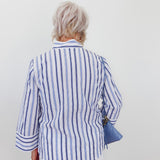Person wearing a blue and white striped shirt against a plain background