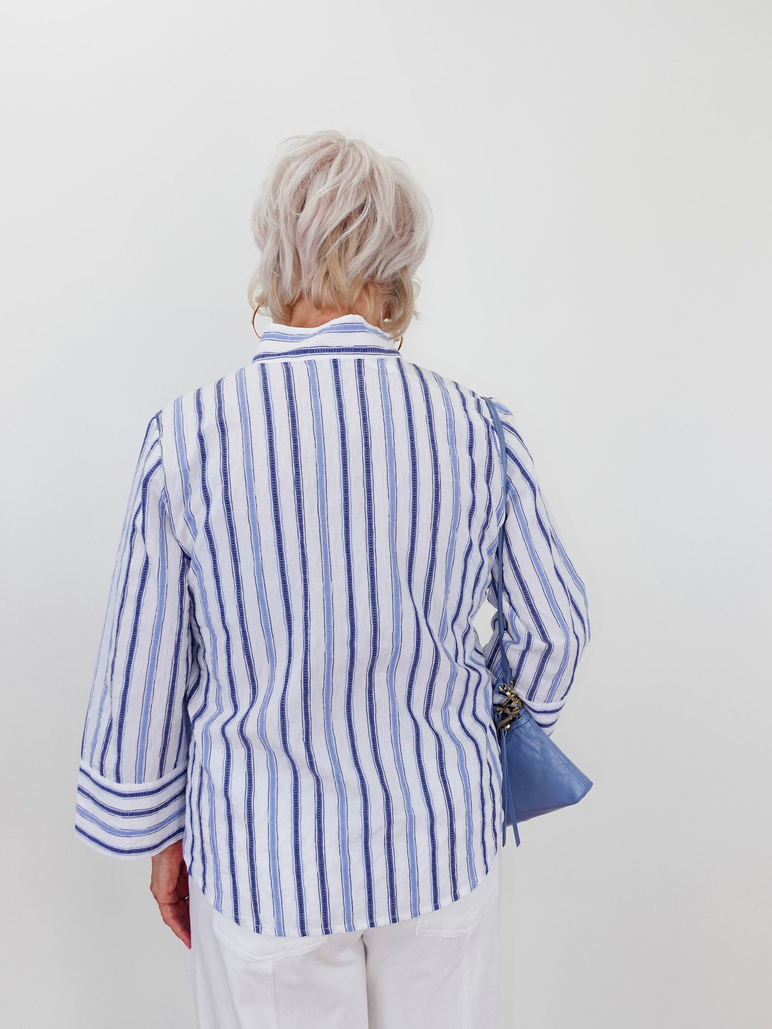 Person wearing a blue and white striped shirt against a plain background