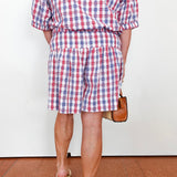 Person wearing a red, white, and blue checkered outfit with shorts and a top.