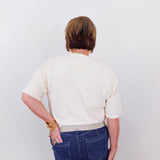 Person wearing a white shirt and blue jeans against a plain background