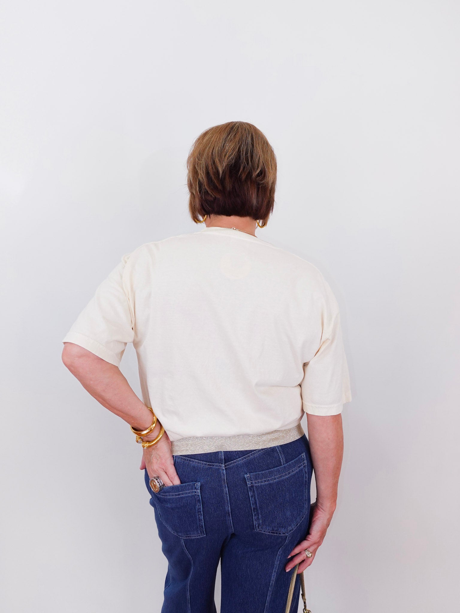 Person wearing a white shirt and blue jeans against a plain background
