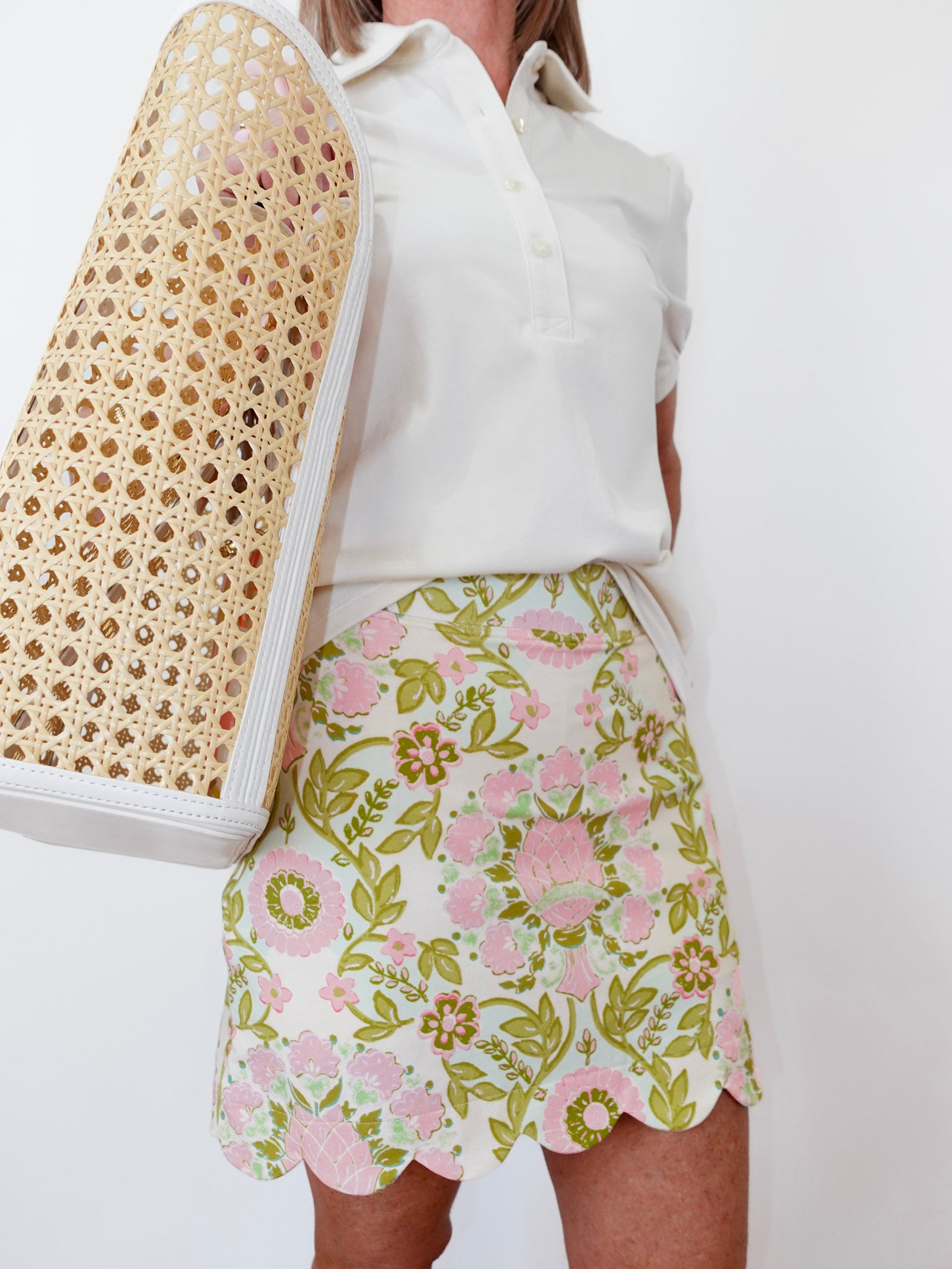 Person wearing a white blouse and floral skirt with a textured bag.