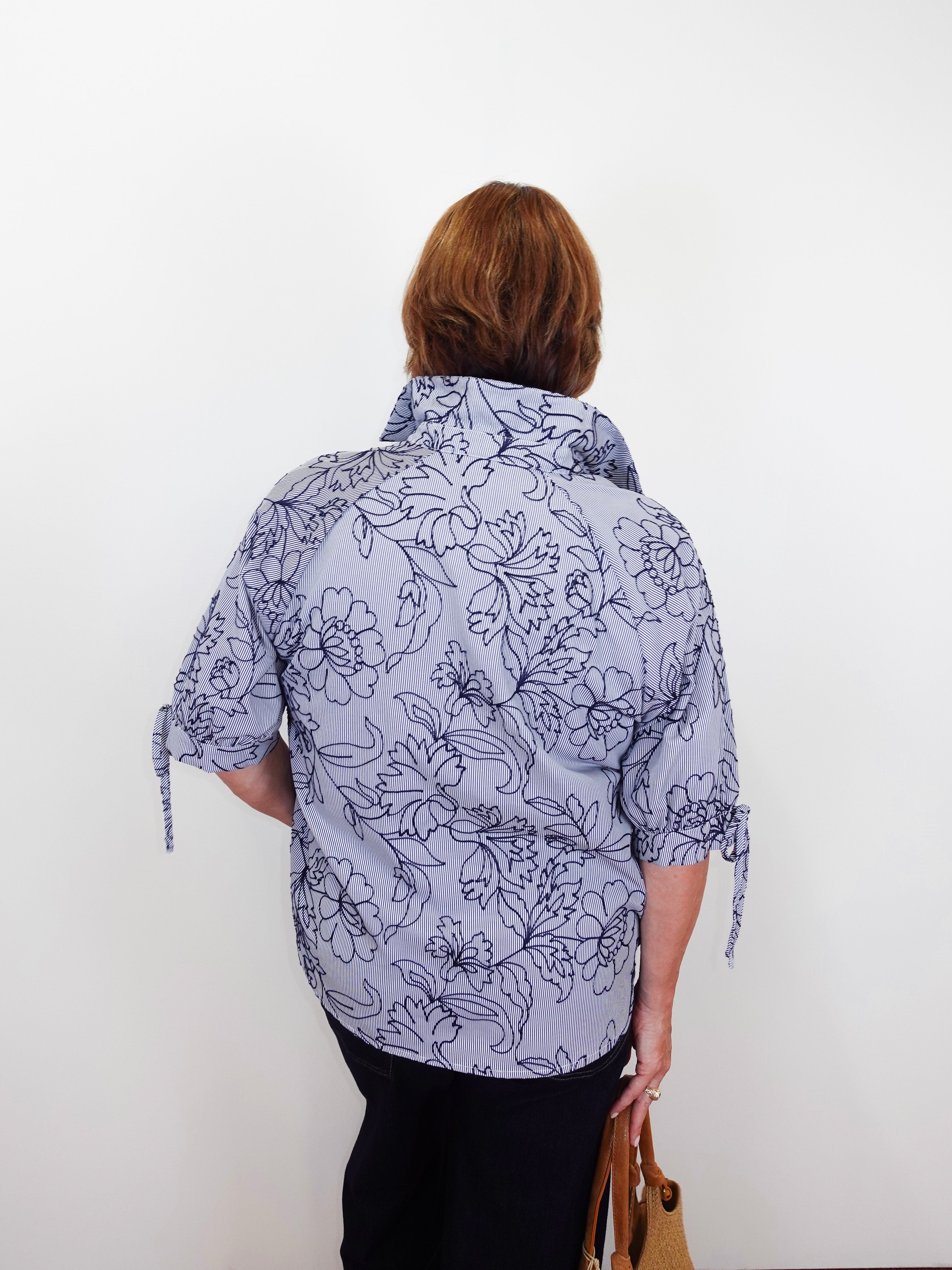 Person wearing a floral-patterned shirt against a white background