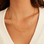 Gold necklace on a person wearing a white sweater