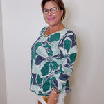 Woman wearing a floral patterned top against a white wall