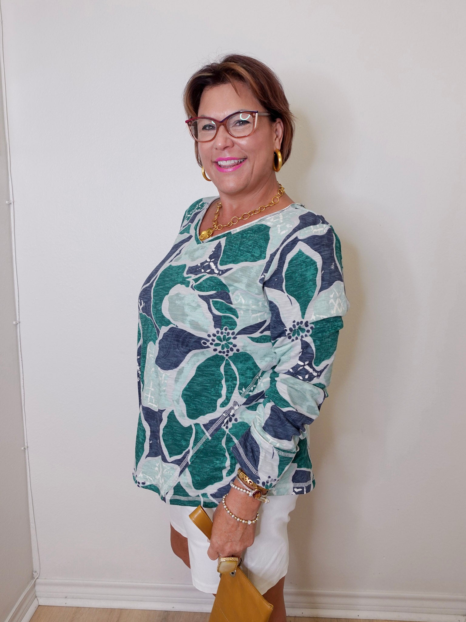 Woman wearing a floral patterned top against a white wall