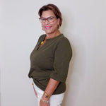 Woman wearing a green top and white shorts against a plain background
