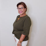 Woman wearing a green top and white shorts against a plain background