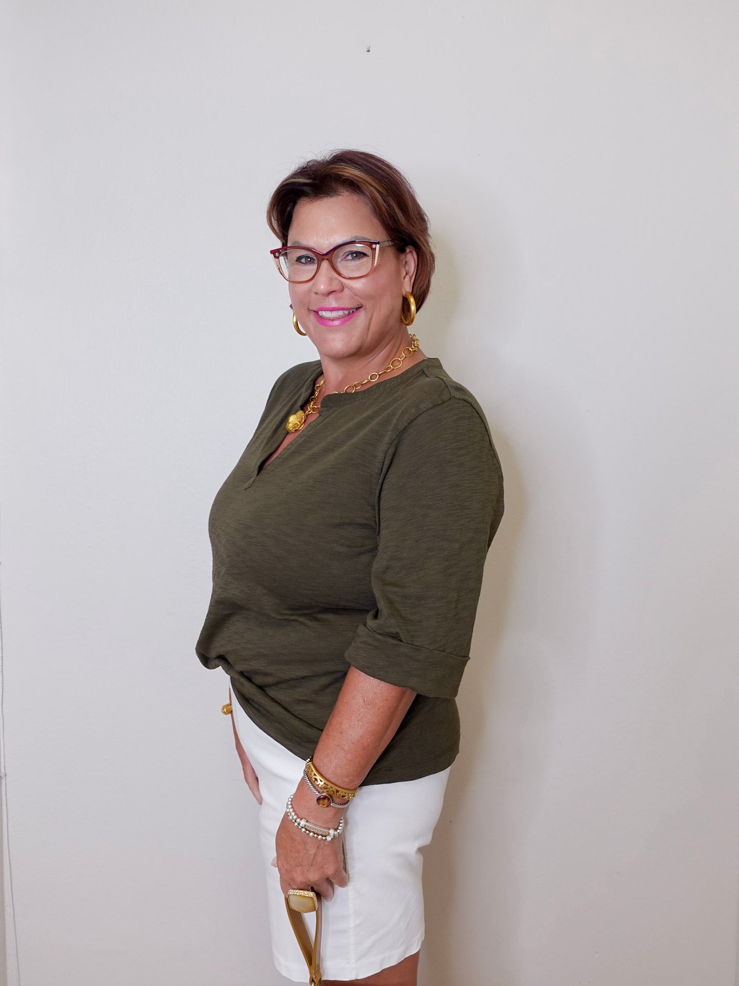 Woman wearing a green top and white shorts against a plain background