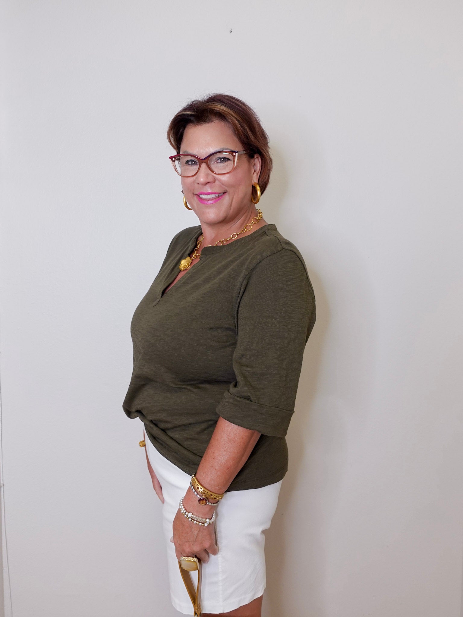 Woman wearing a green top and white shorts against a plain background