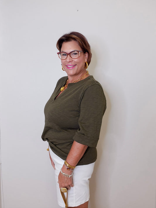 Woman wearing a green top and white shorts against a plain background
