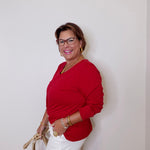 Woman wearing a red top and white shorts against a plain background