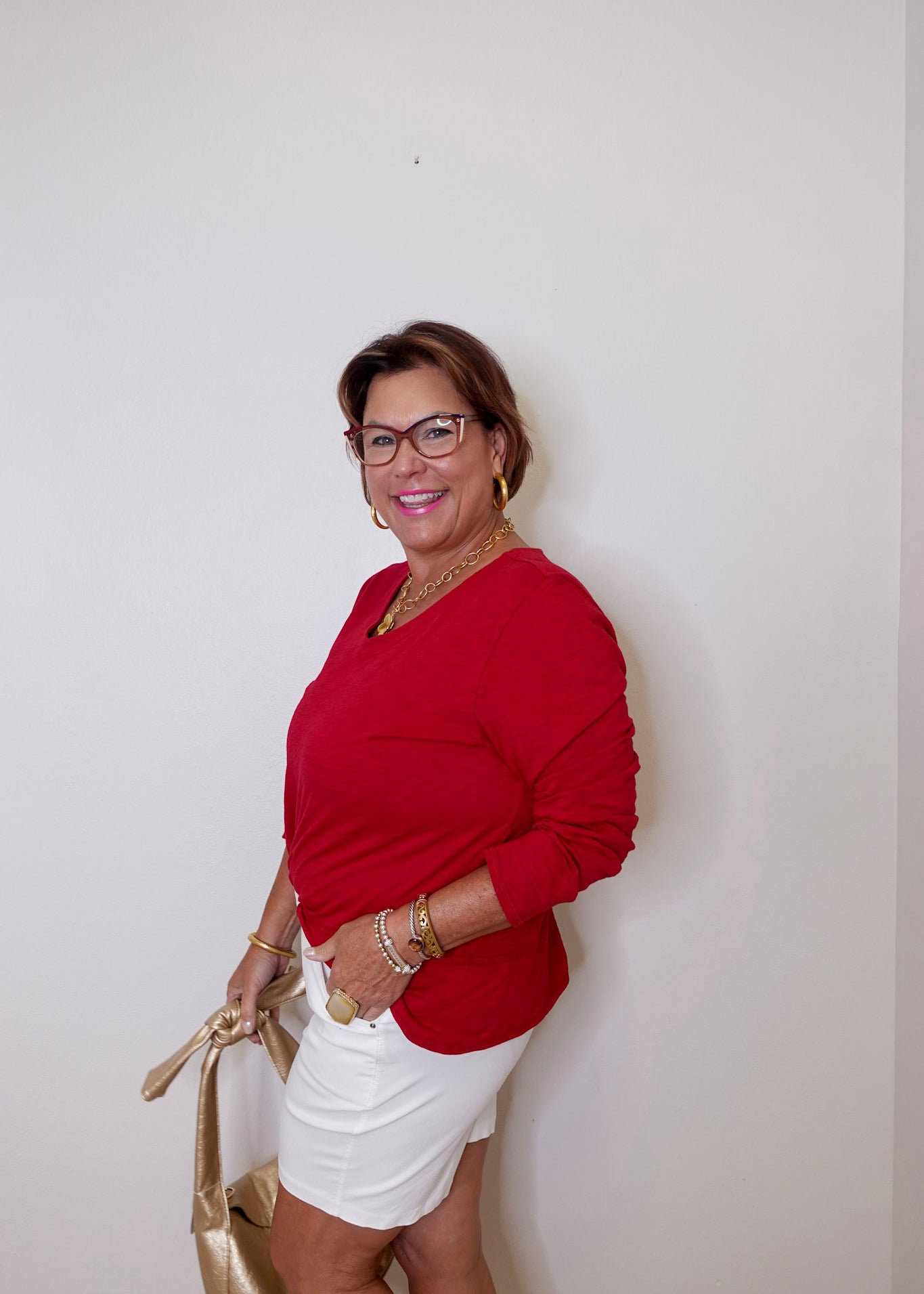 Woman wearing a red top and white shorts against a plain background