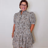 Woman wearing a patterned dress against a plain background