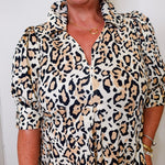 Person wearing a leopard print dress with a plain background