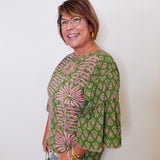 Woman wearing a green and pink patterned blouse against a white background