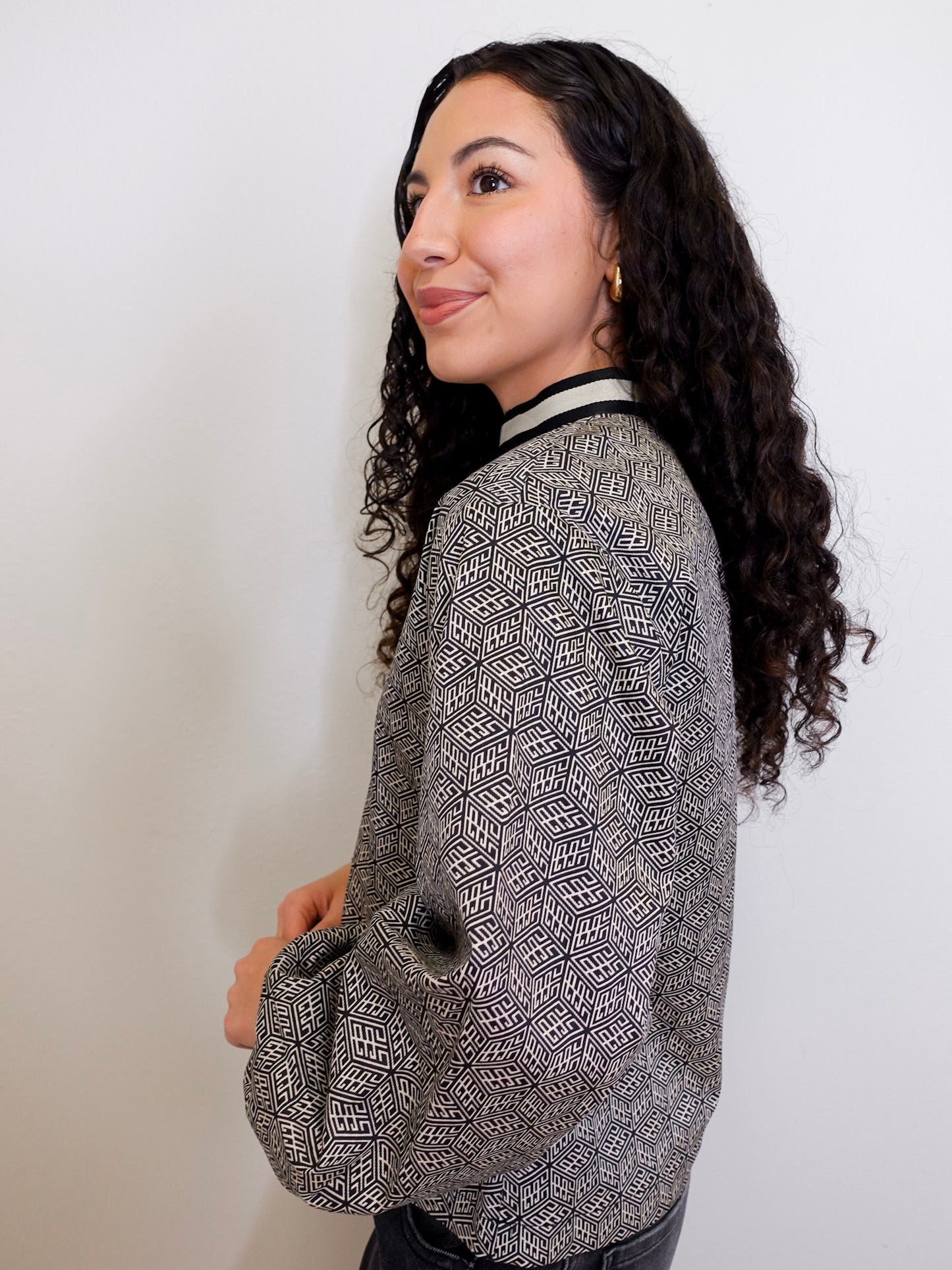 Woman wearing a patterned top against a plain background