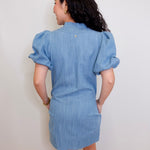 Woman wearing a blue denim dress against a white wall