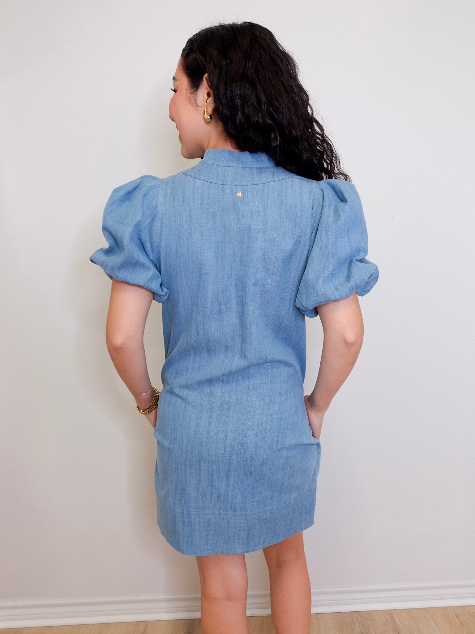 Woman wearing a blue denim dress against a white wall